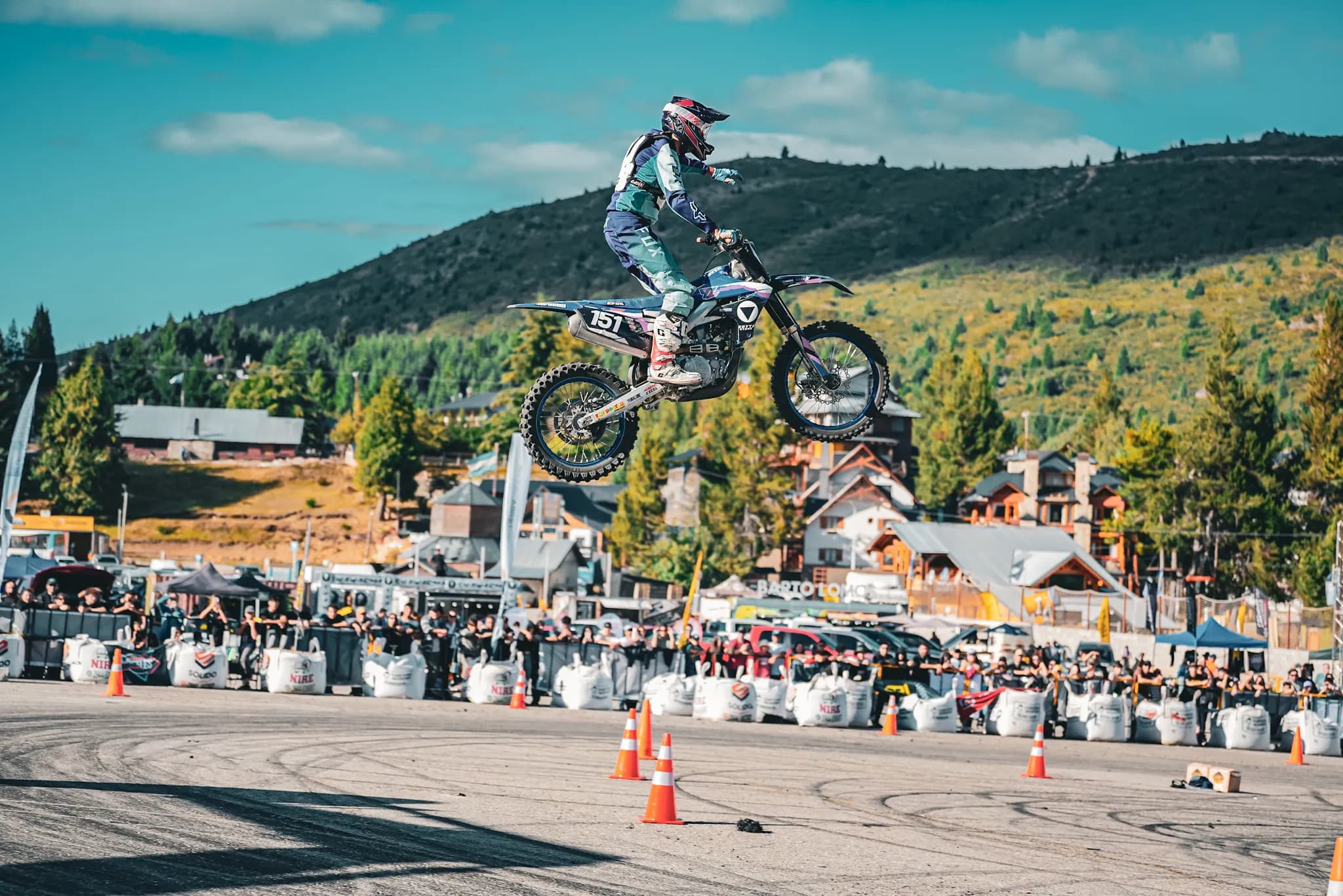 Moto en pleno salto con la villa, el público y el Cerro Catedral de fondo