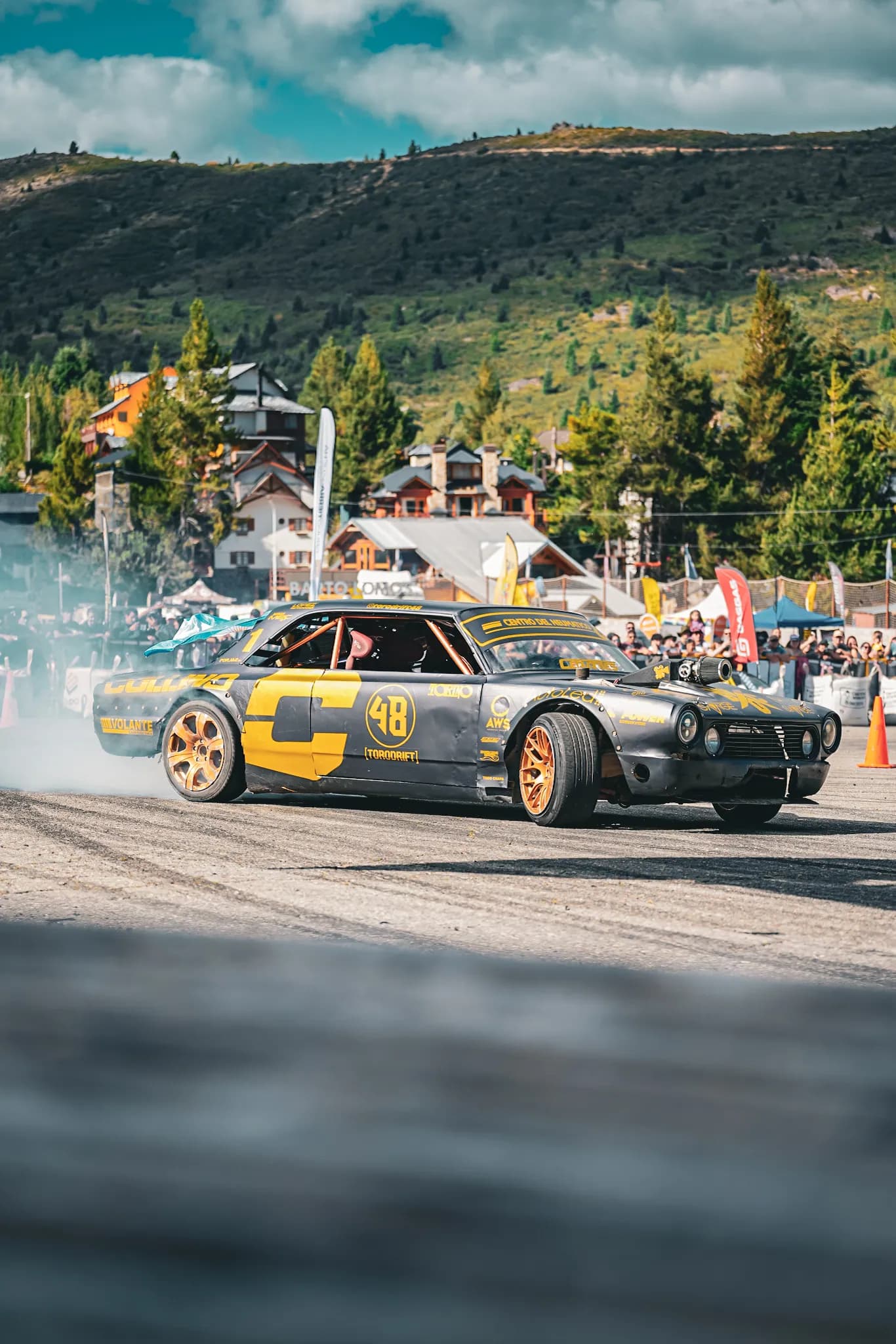 Torino de drift derrapando con humo frente a la villa del Cerro Catedral